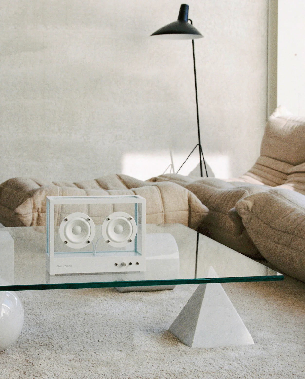 Transparent högtalare på glasbord i vardagsrum