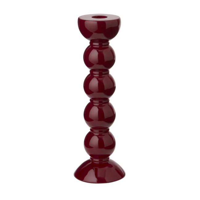 En vinröd ljusstake med hÀrlig bubblig fot mot vit bakgrund.