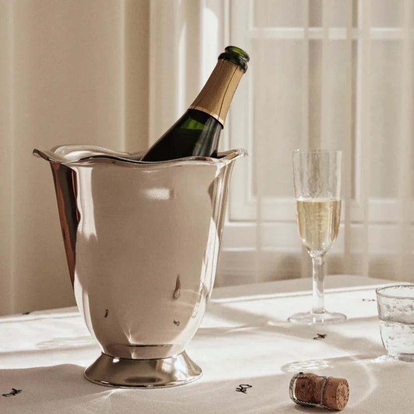 Vinkylare i aluminium med silverfinish på ett bord med vit duk och ett champagneglas