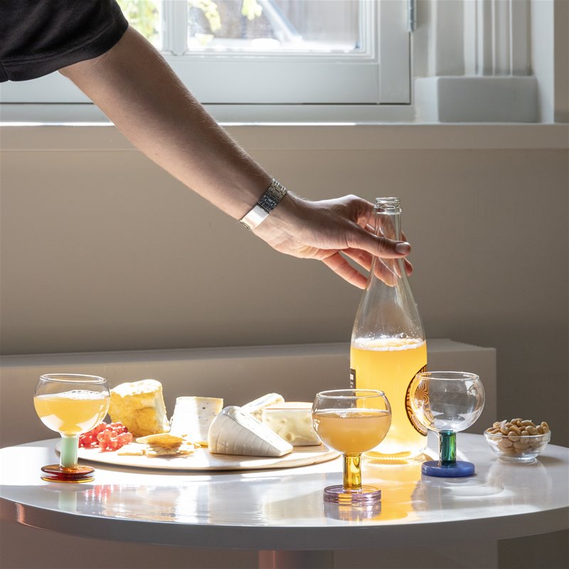 Ett bord dukat med vinglas i olika färger från & Klevering, orangevin och franska ostar.