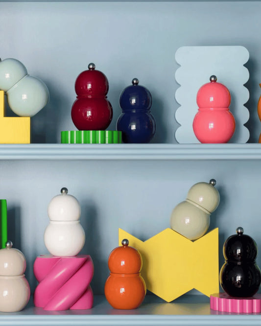 Färgglada salt- och pepparkvarnar ståendes på hylla