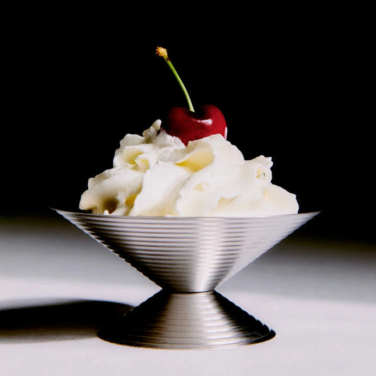 Bägare i rostfritt stål från Service Projects med grädde i och ett körsbär på toppen.