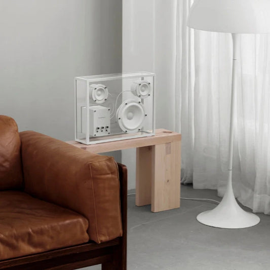 Vit och transparent högtalare i rum på bord bakom soffa