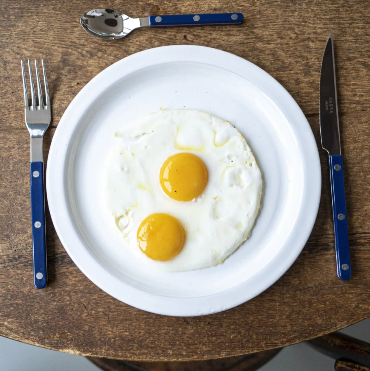 sabre bistrot bestick marinblå dukat med stekt ägg på tallrik