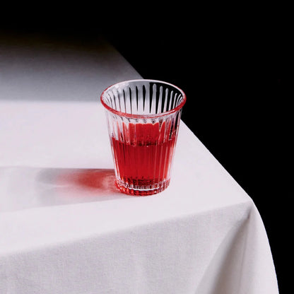 Service Projects Bodega Canteen glas med röd dryck I ståendes på ett bor med vit duk och svart bakgrund.