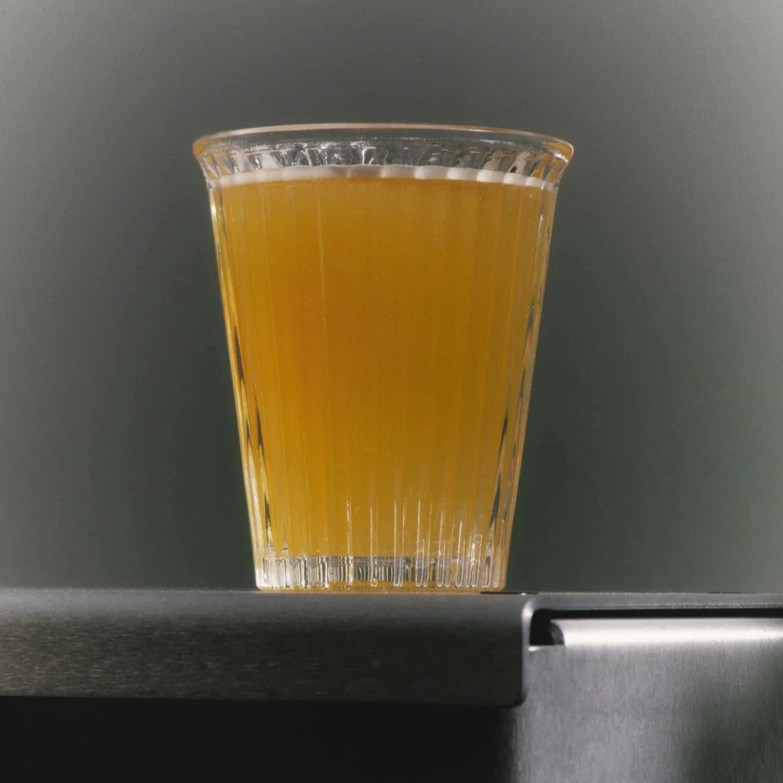 Dryckesglas från Service Projects med öl i fotad underifrån med grå bakgrund. 