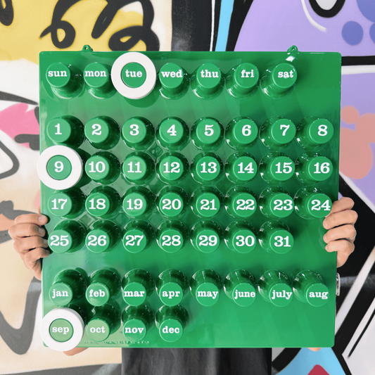 Grön väggkalendern med vita ringar som en kille håller i. Graffitibakgrund