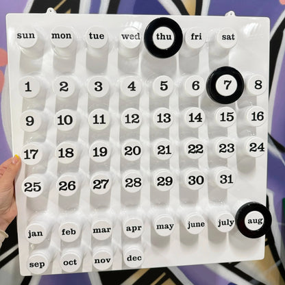 Vit väggkalender från Italien men svarta ringar på hålls mot en graffitivägg på Mon Bistro 