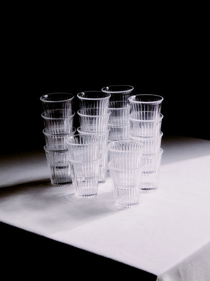 Massa glas från Service Projects staplade på ett bord med vit duk och svart bakgrund