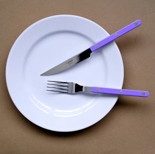 Sabre bistrot bestickset lila på vit tallrik mot brun bakgrund