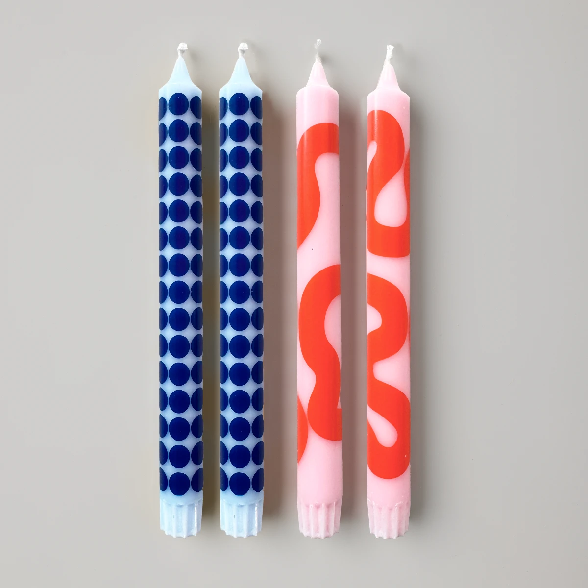 fyra stearinljus två blå med moster och två rosa med mönster mot vit bakgrund