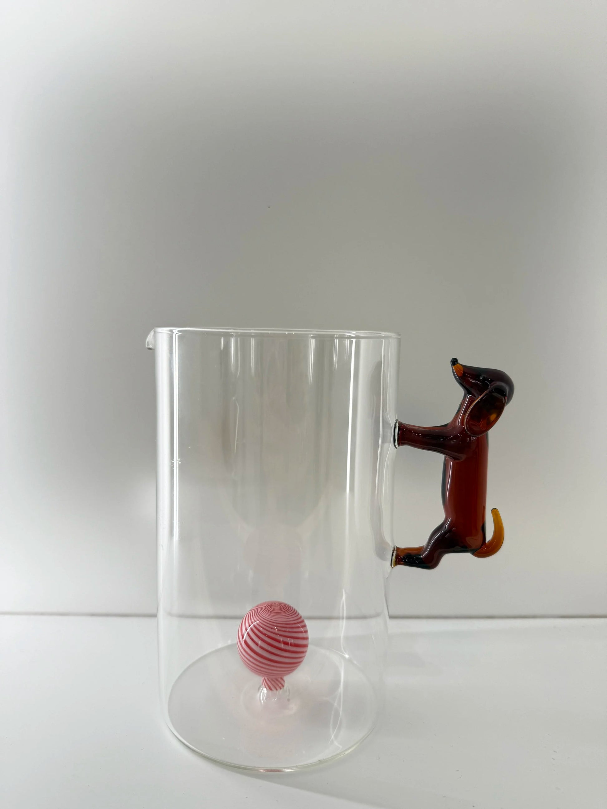 En bringare / karaff med en tax som handtag och en boll i röd och vit inuti