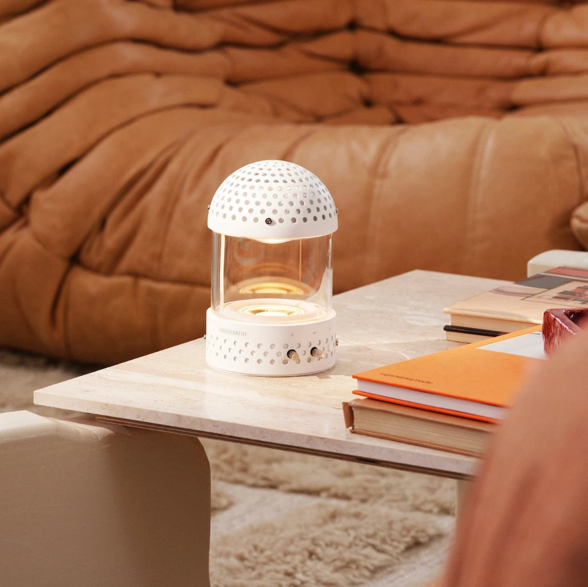 Transparent Light speaker på ett soffbord med en brun skinnsoffa i bakgrunden