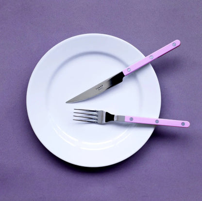sabre bistrot bestickset kniv gaffel på vit tallrik mot lila bakgrund