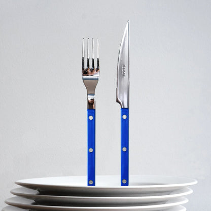 sabre bistrot kniv gaffel ståendes på hög med vita tallrikar